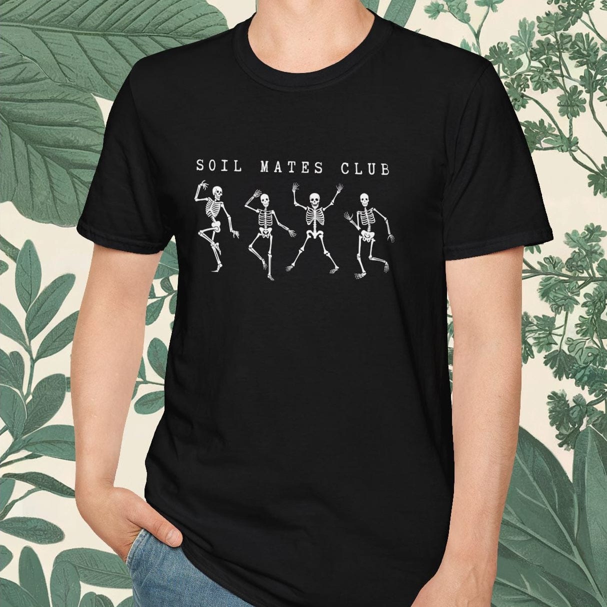 Person wearing a black t-shirt with 'SOIL MATES CLUB' text and skeleton graphics, standing against a leafy background.