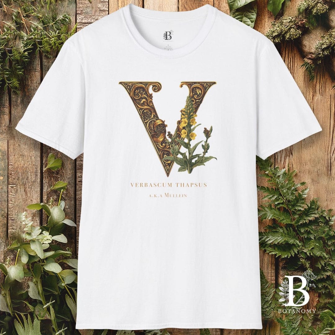 White t-shirt with decorative letter 'V' design on a wooden background with greenery