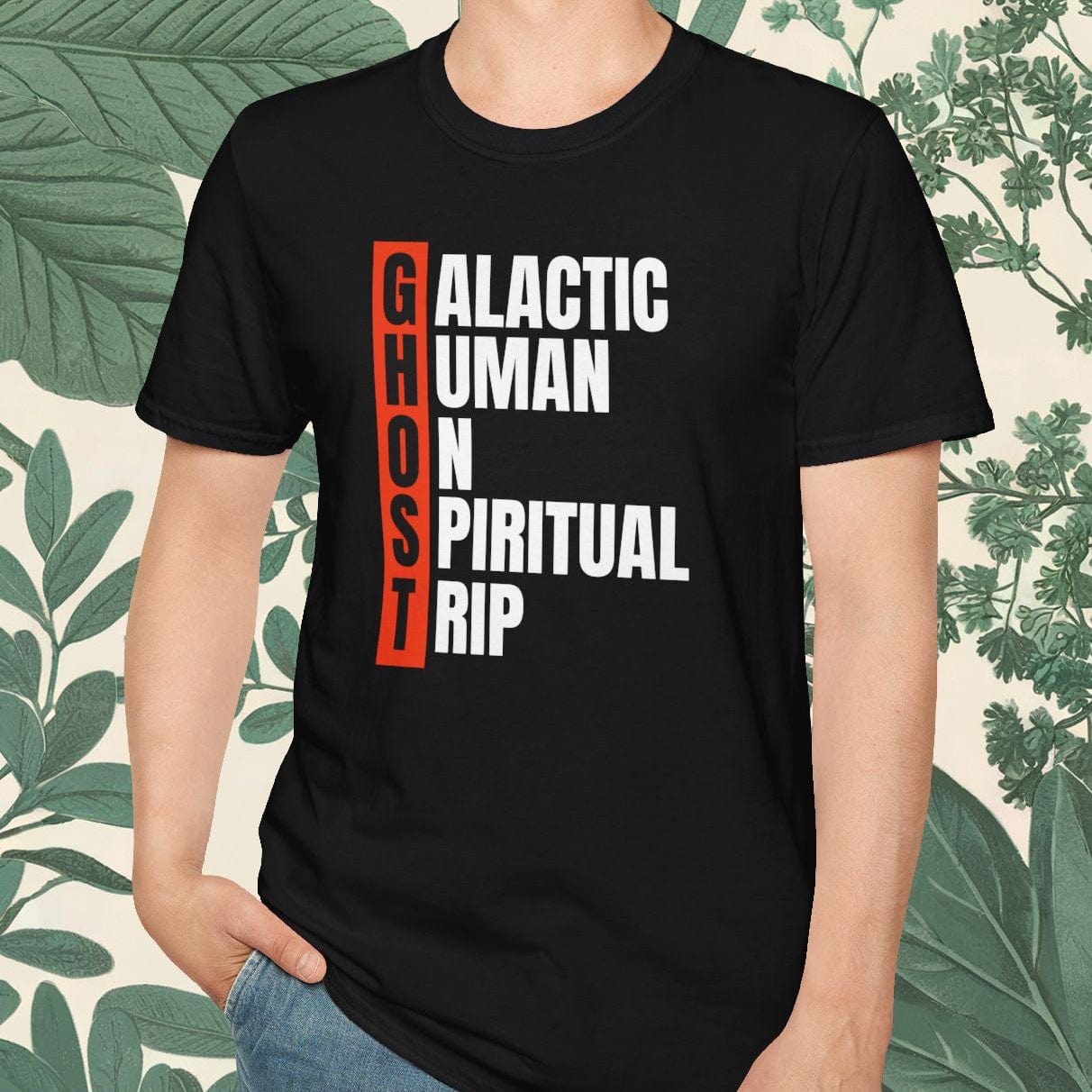 Person wearing a black t-shirt with text design, standing against a leafy background