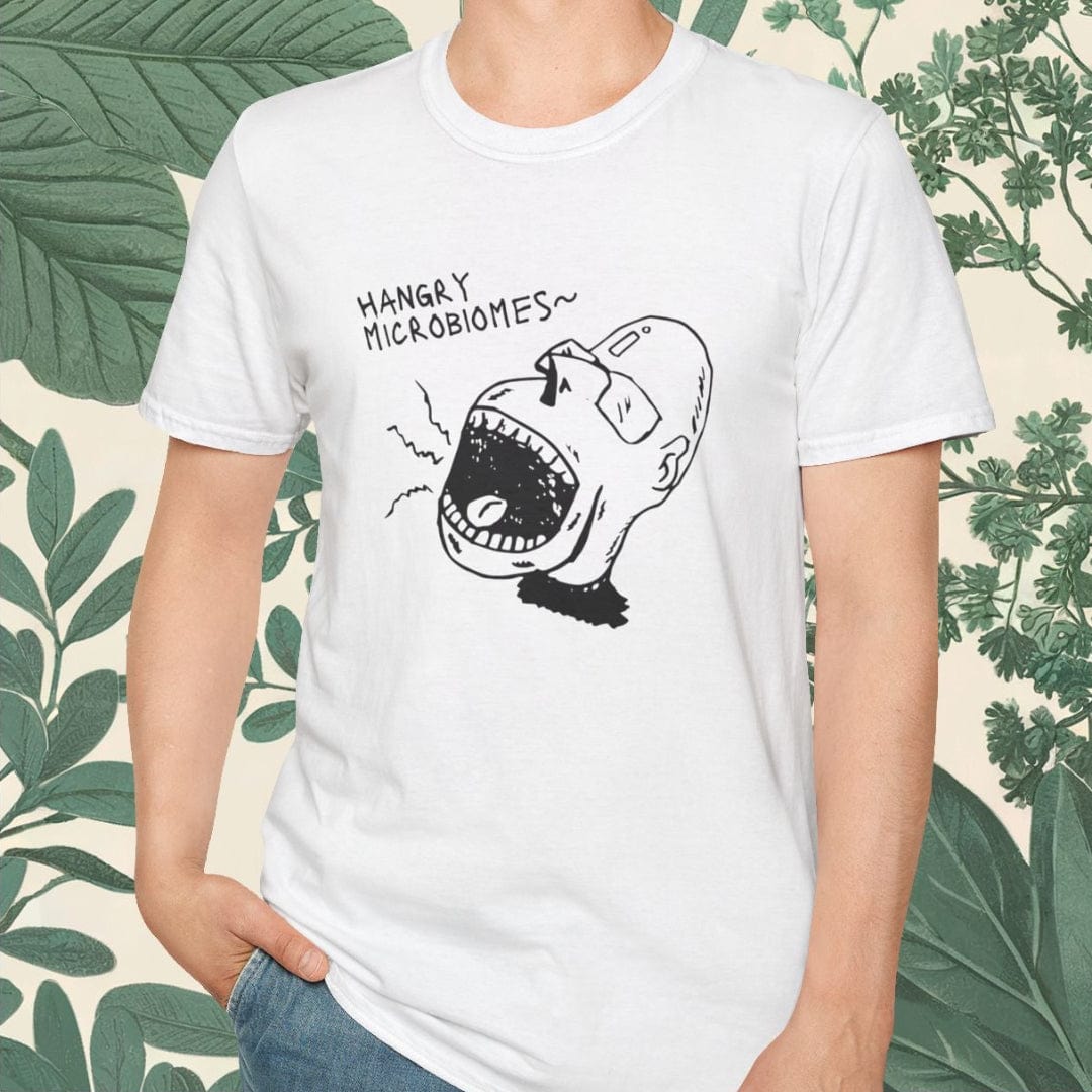 Person wearing a white t-shirt with a graphic design and text, standing against a leafy background.