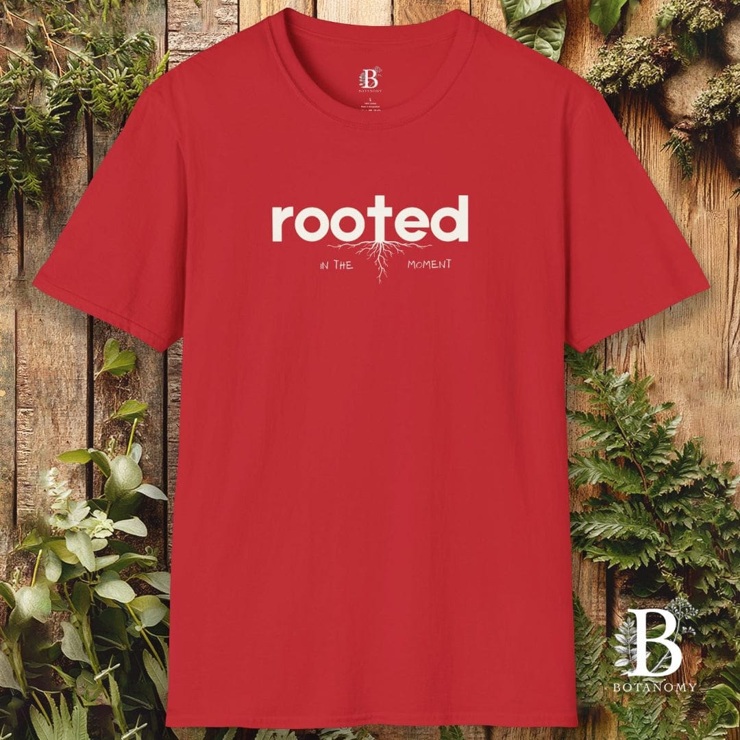 Red t-shirt with 'rooted' text on a wooden background with plants