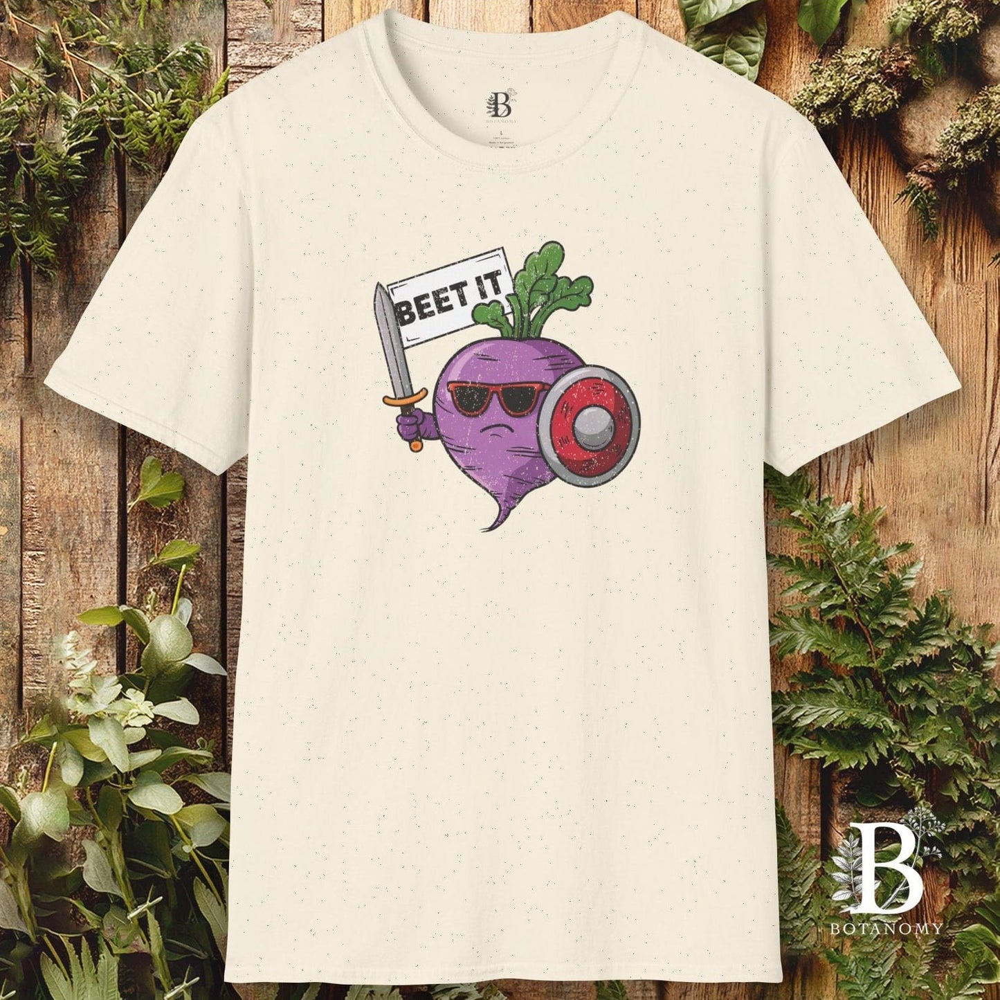 Beige t-shirt with a graphic of a beet wearing sunglasses and holding a sign that says 'BEET IT' on a wooden background.
