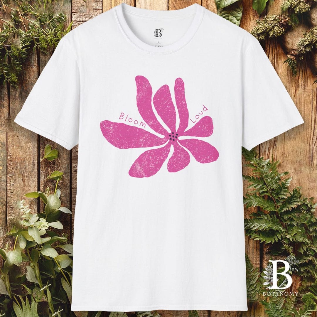 White t-shirt with pink floral design and brand logo on a wooden background