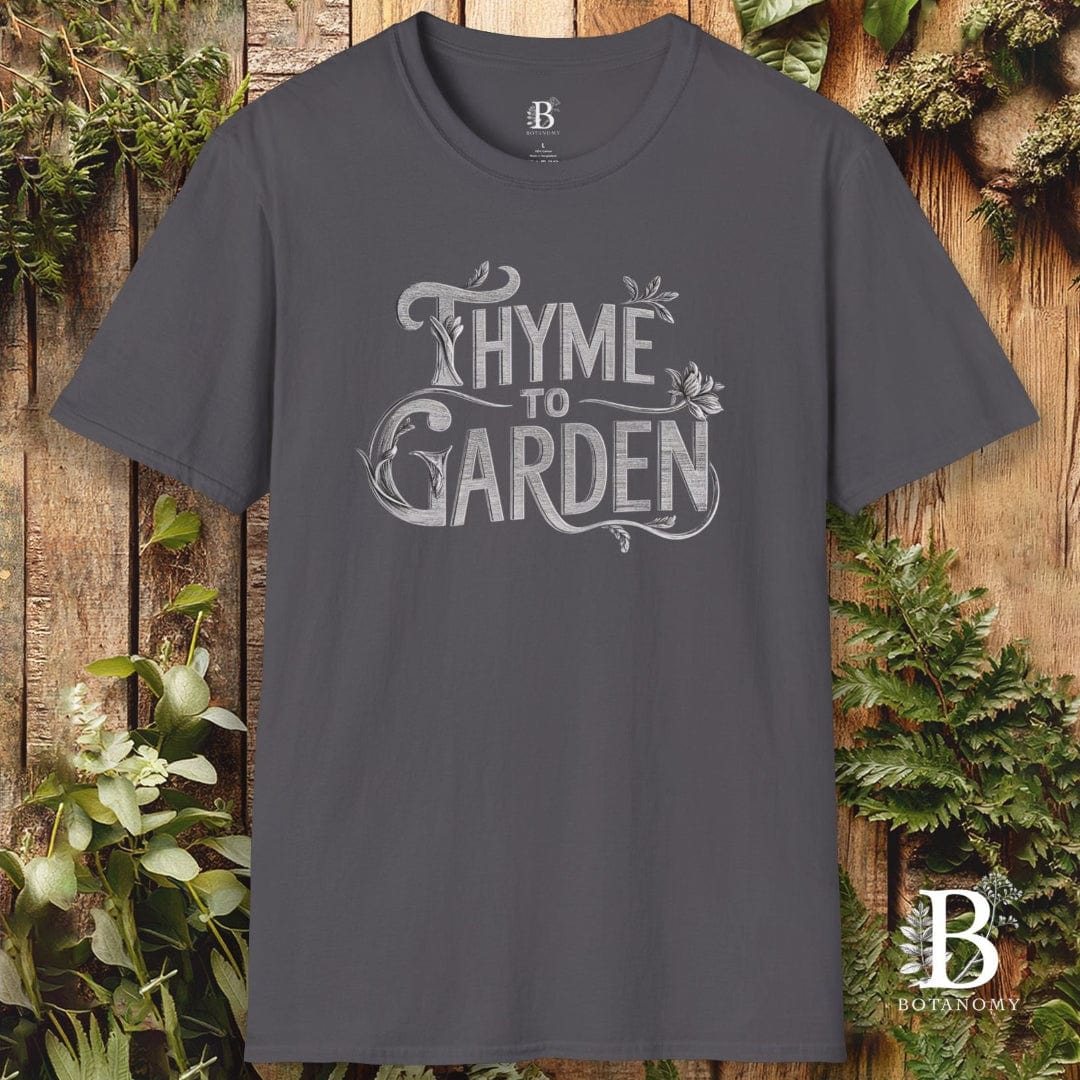 Gray t-shirt with 'Thyme to Garden' text on a wooden background with plants