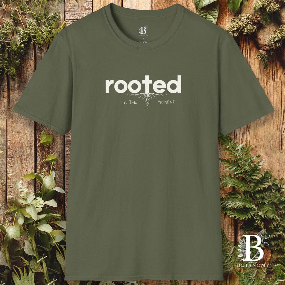 Green t-shirt with 'rooted' text on a wooden background with plants