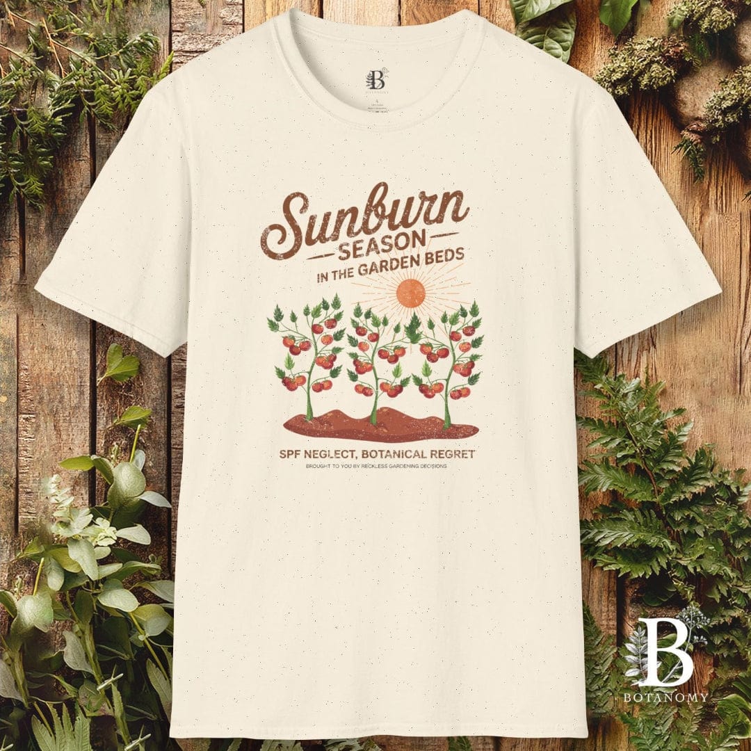 White t-shirt with 'Sunburn Season' graphic design on a wooden background with plants.