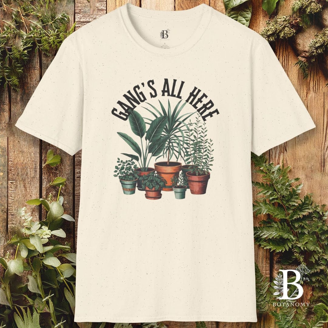 Beige t-shirt with plant design and text 'Gangs All Here' on a wooden background