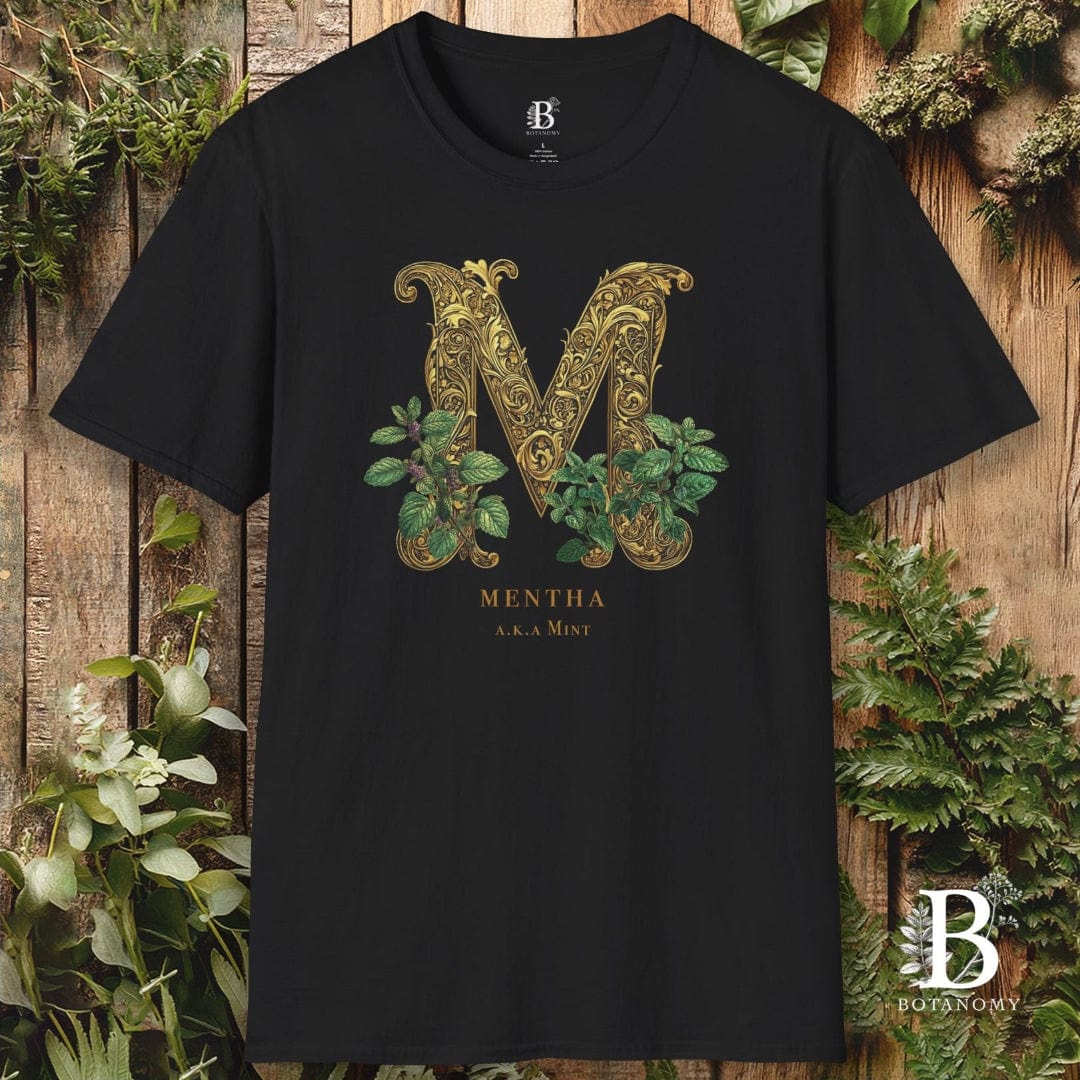 Black t-shirt with decorative 'M' design and plant elements on a wooden background