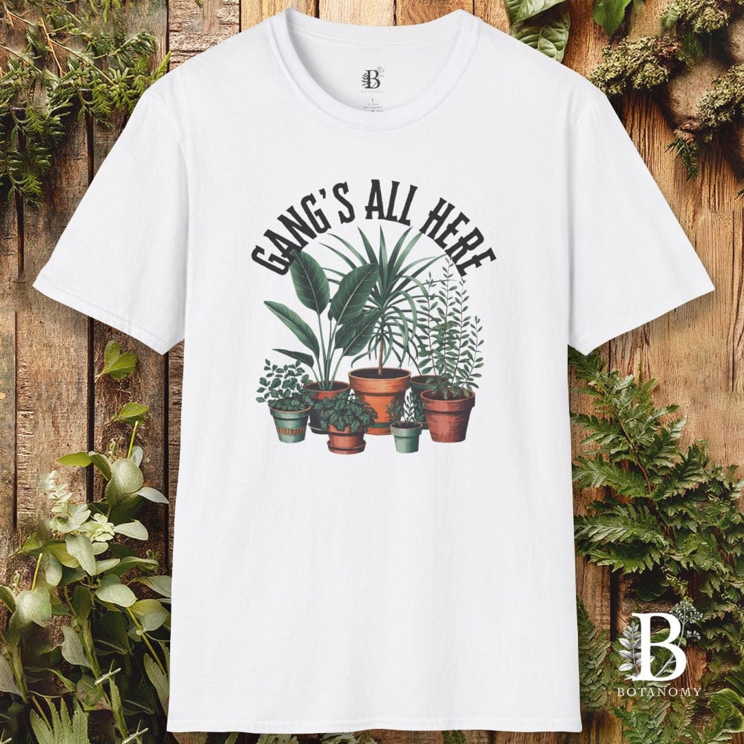 White t-shirt with plant design and text 'Gangs All Here' on a wooden background