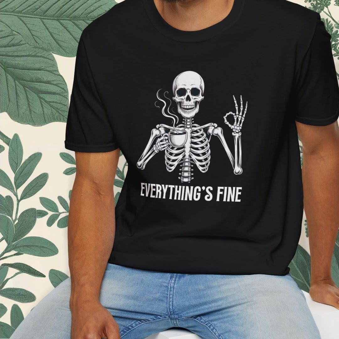 Man wearing a black t-shirt with a skeleton graphic and 'Everything's Fine' text, sitting on a white stool with a green leafy background.