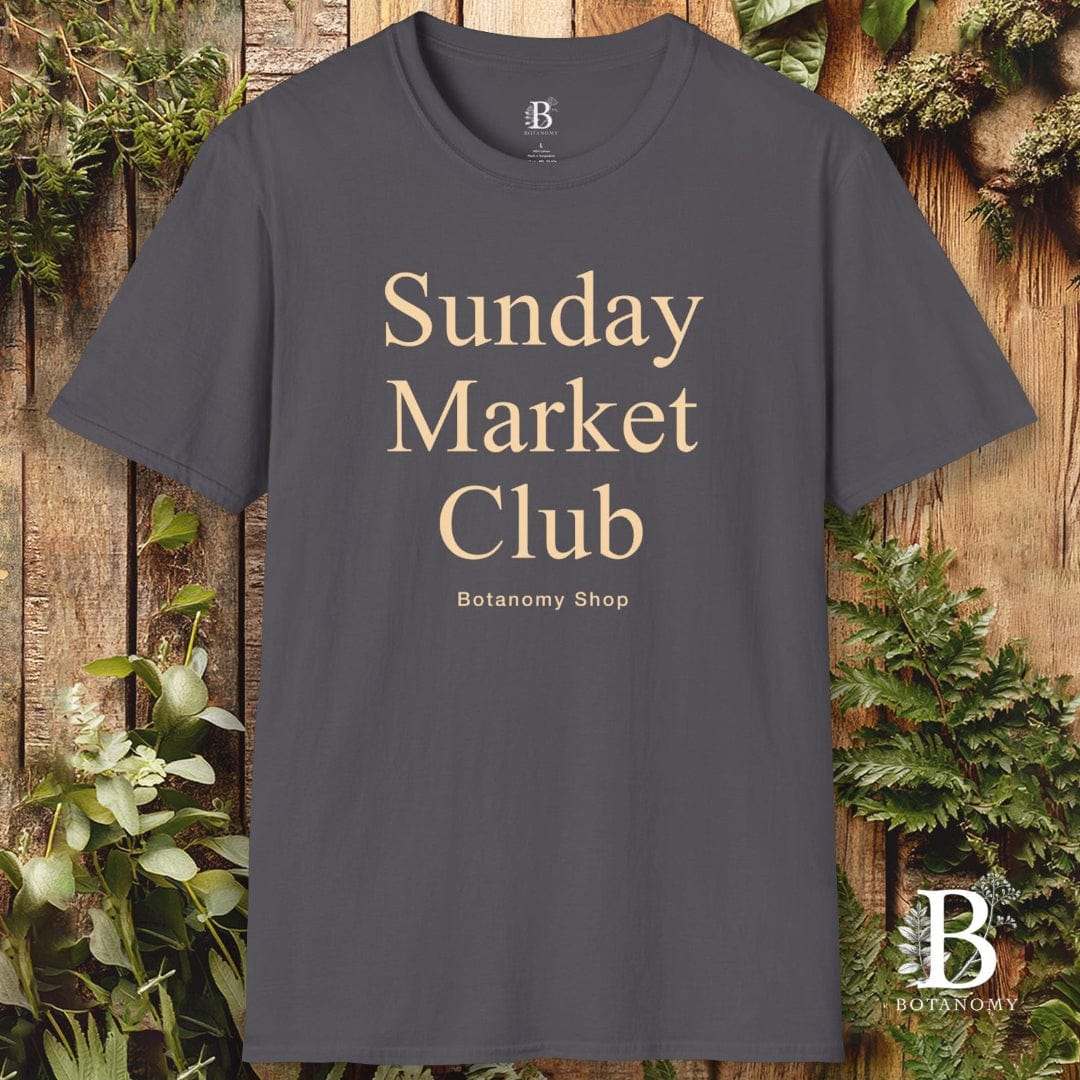 Gray t-shirt with 'Sunday Market Club' text on a wooden background with plants