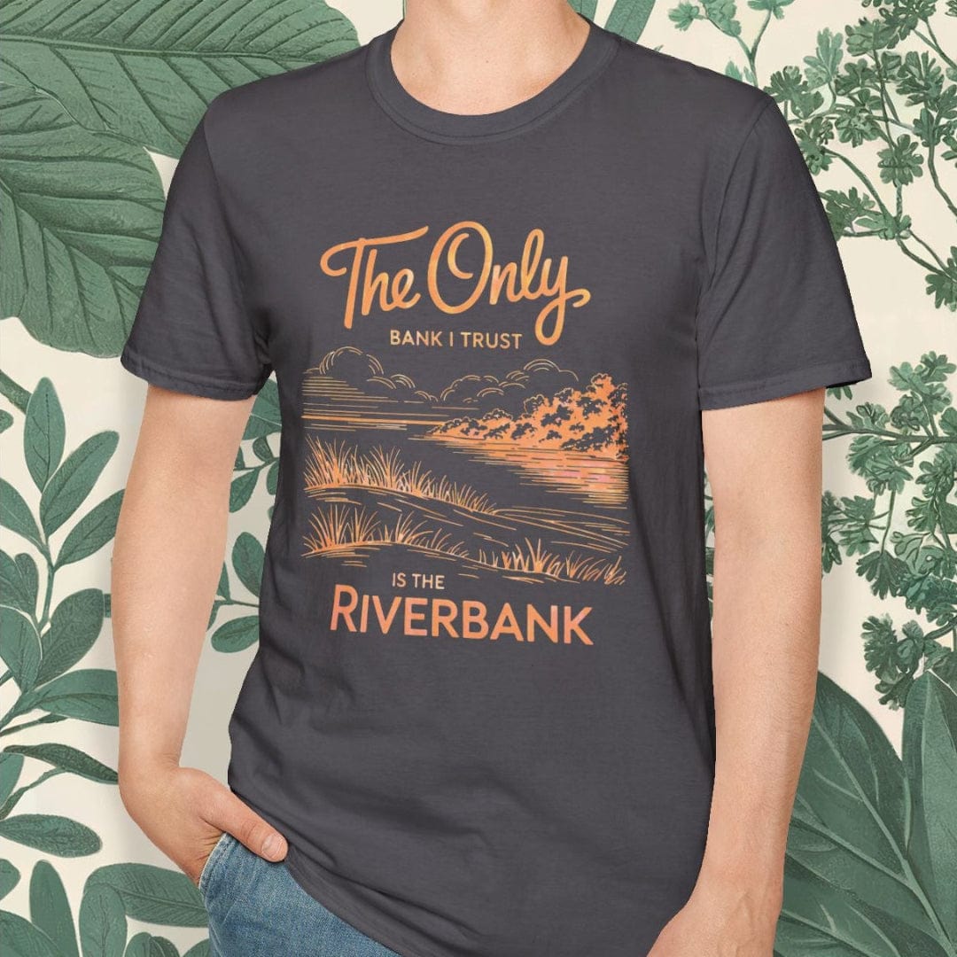 Man wearing a t-shirt with a scenic design and text, standing against a leafy background