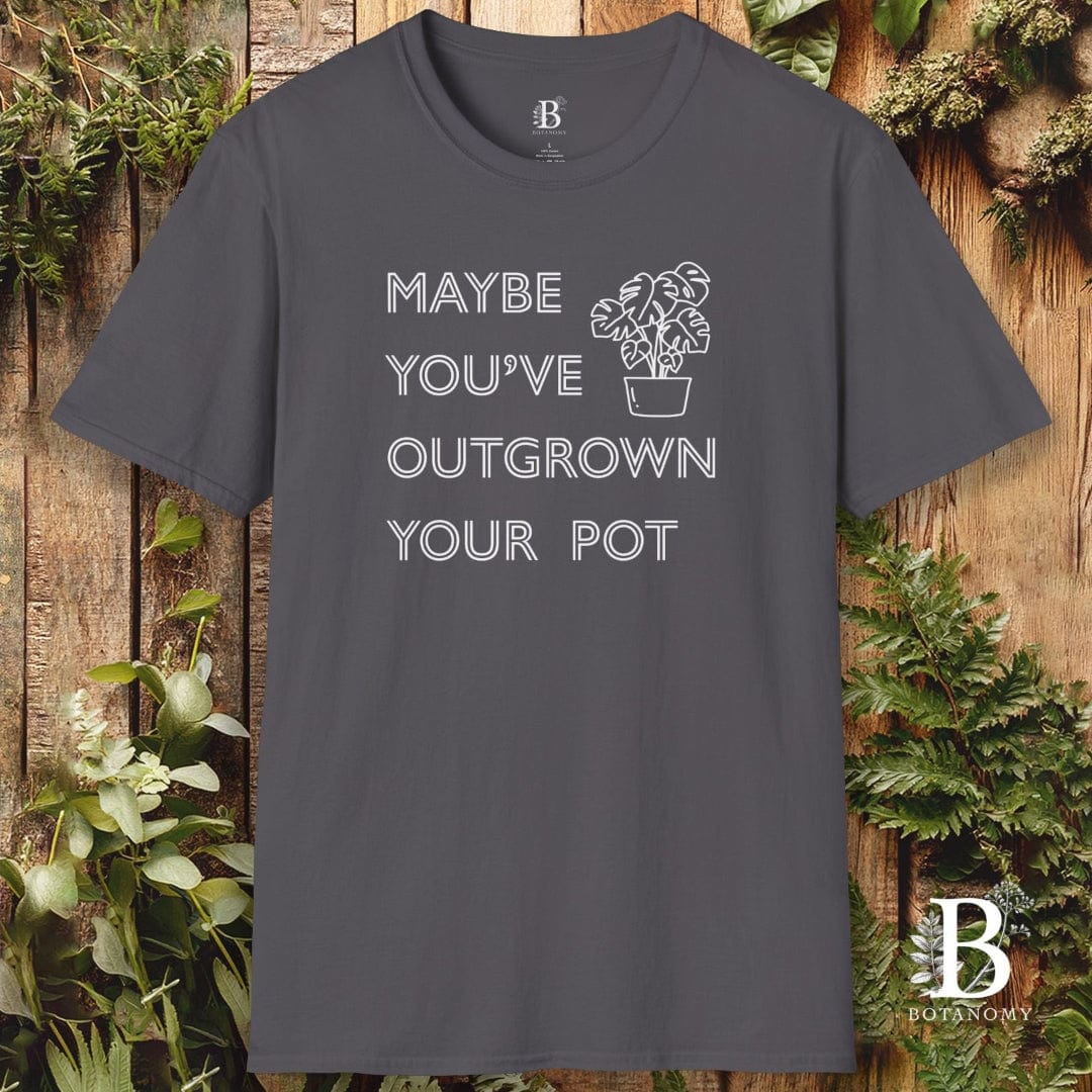 Gray t-shirt with text 'Maybe you've outgrown your pot' on a wooden background with plants.