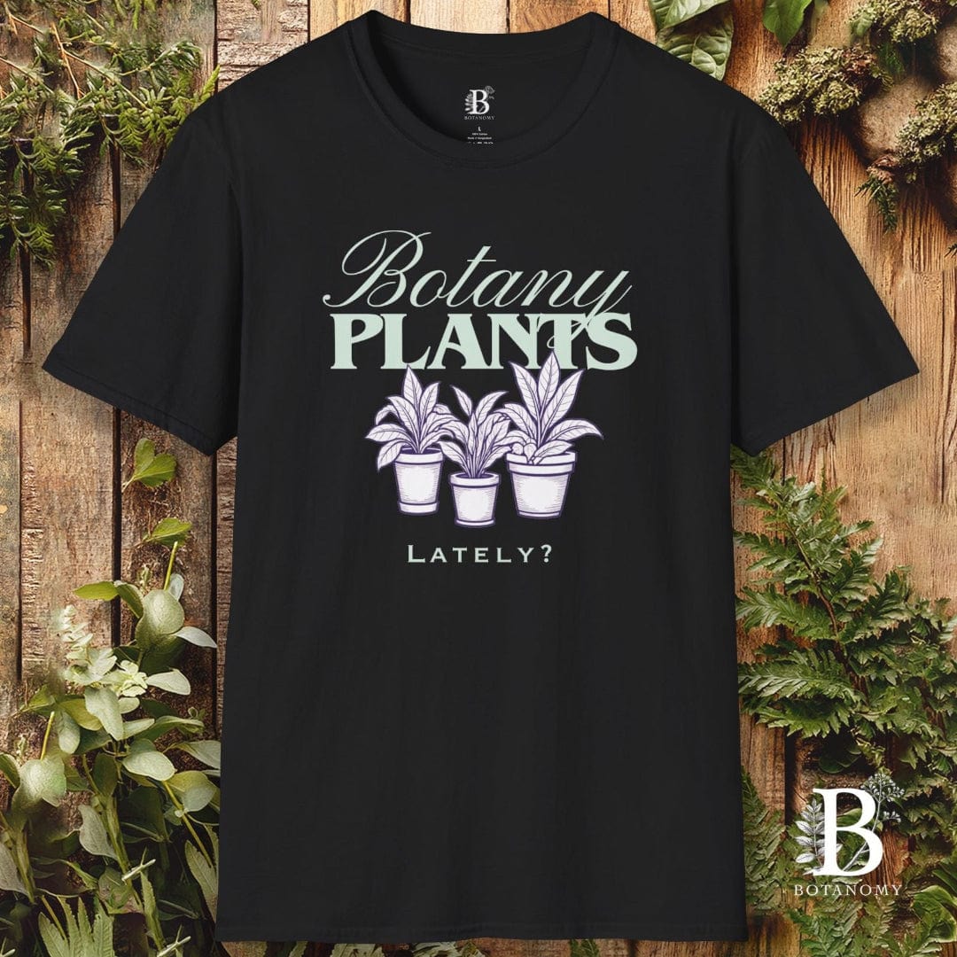 Black t-shirt with 'Botany Plants Lately?' design on a wooden background with plants.