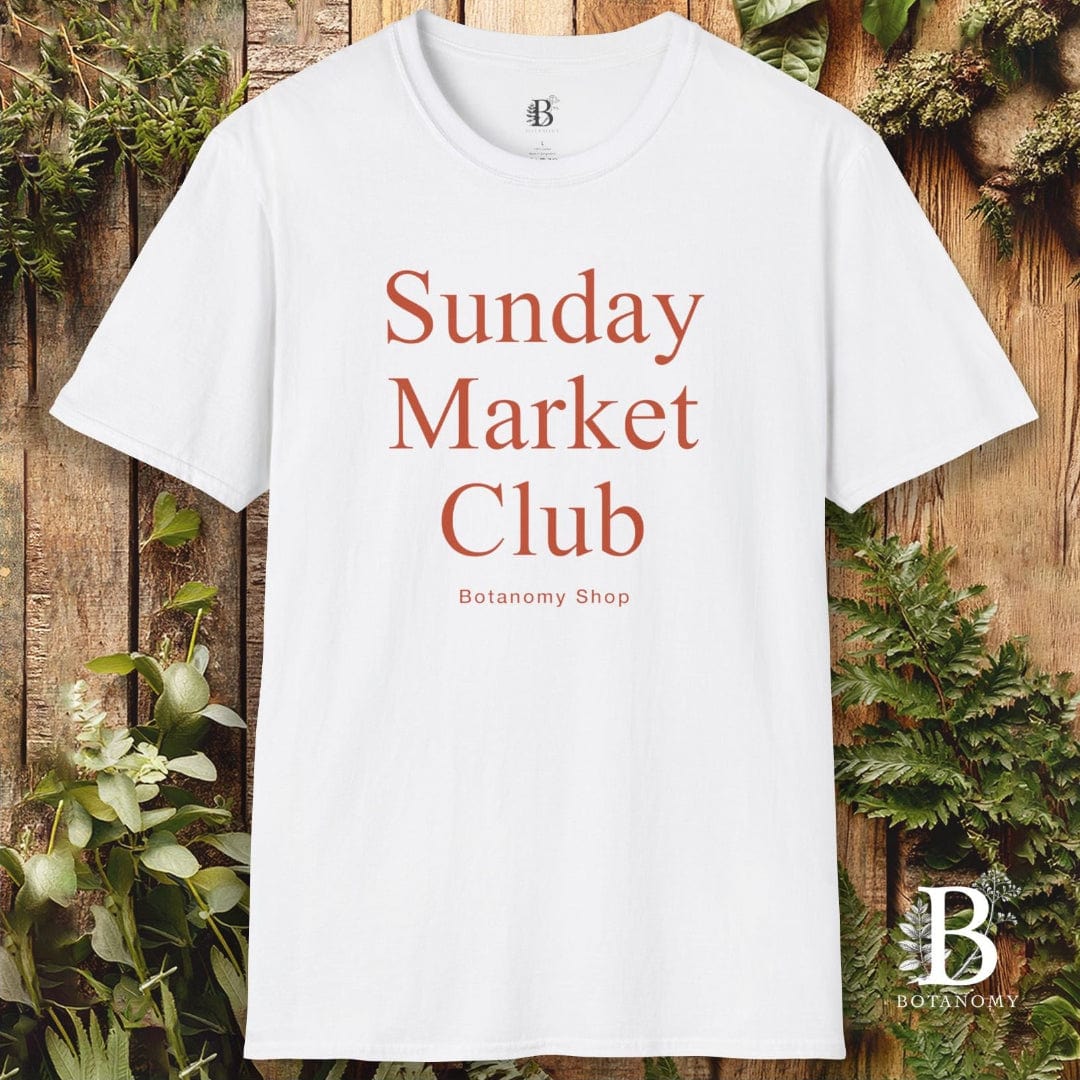White t-shirt with 'Sunday Market Club' text on a wooden background with plants