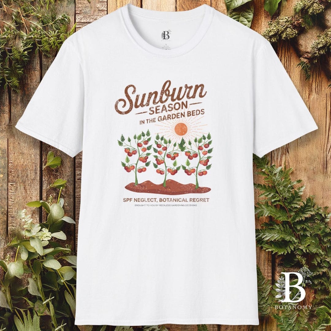White t-shirt with 'Sunburn Season' graphic design on a wooden background with plants.