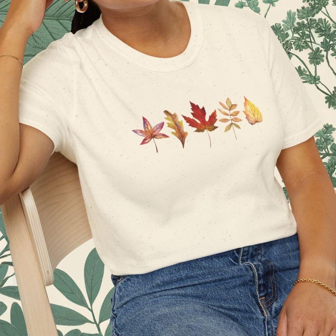 Woman wearing a white t-shirt with leaf design sitting on a chair.