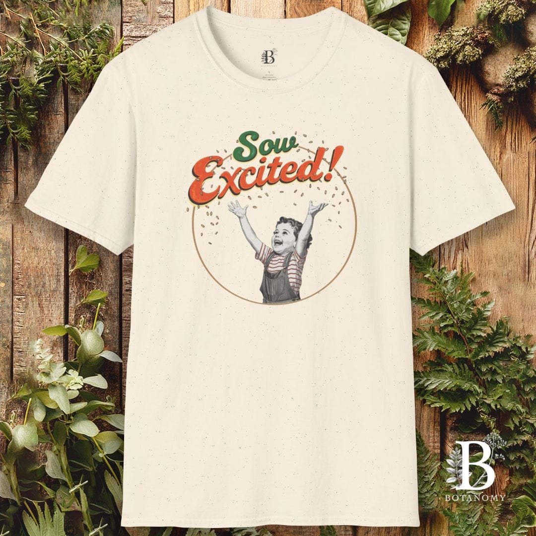 Beige t-shirt with 'Sow Excited!' graphic design on a wooden background with plants.