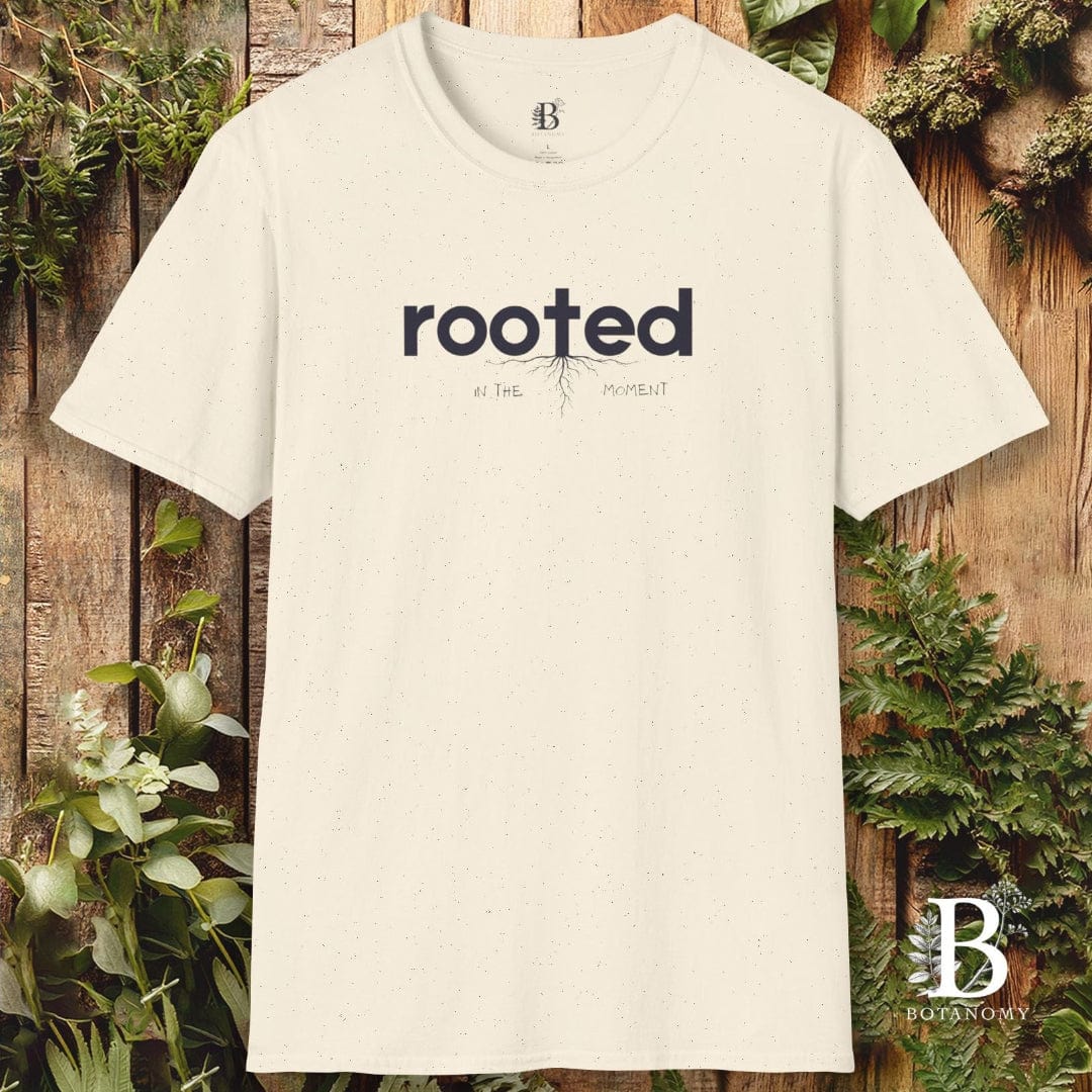 Beige t-shirt with 'rooted' text on a wooden background with plants