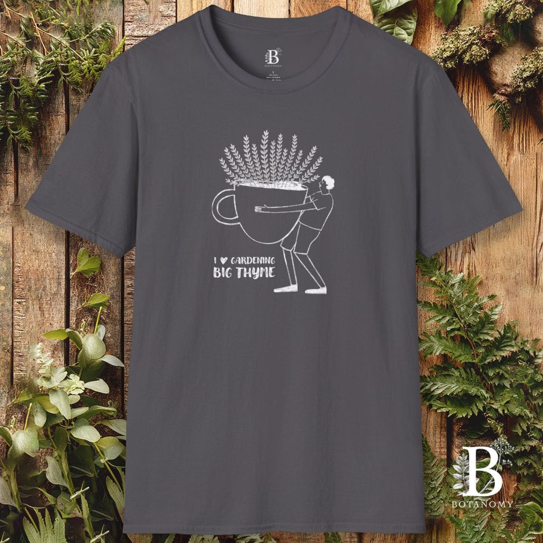 Gray t-shirt with white graphic design on a wooden background with plants