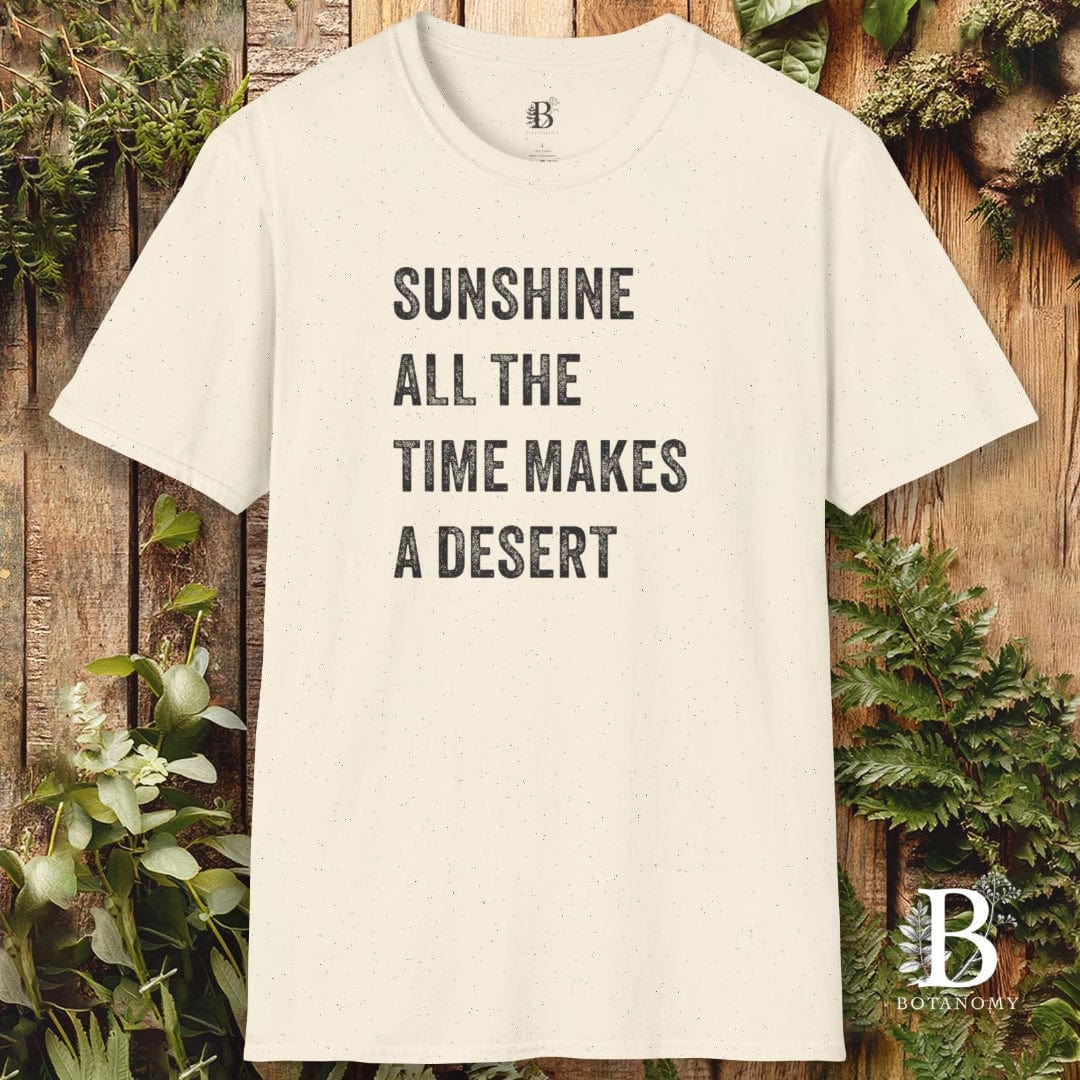 Beige t-shirt with text 'Sunshine all the time makes a desert' on a wooden background with plants.