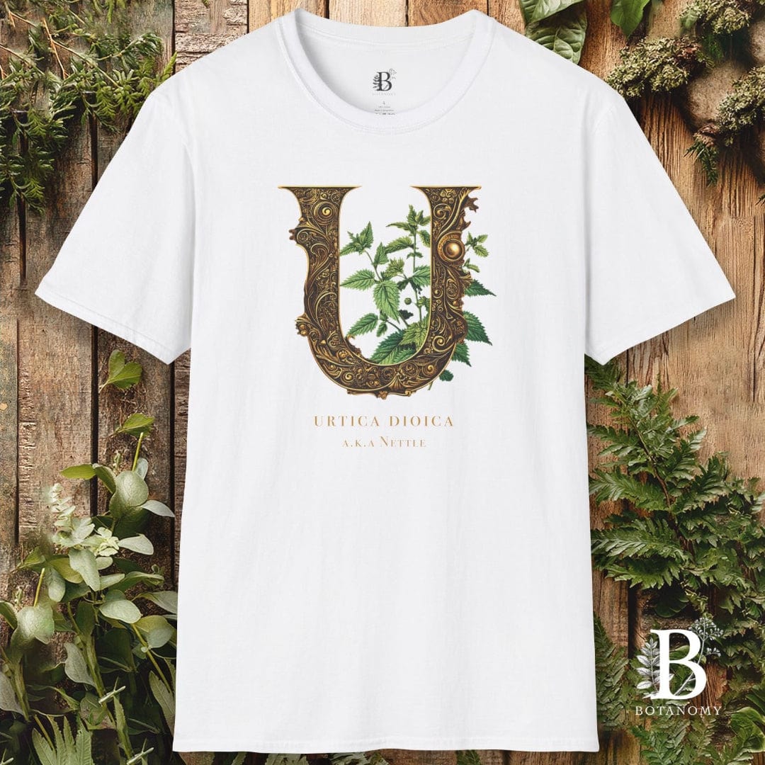 White t-shirt with decorative letter 'U' design on a wooden background with greenery