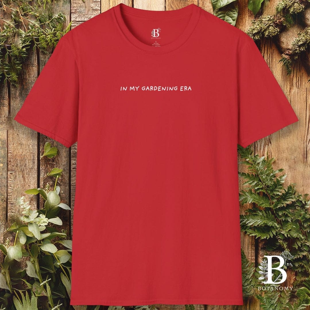 Red t-shirt with 'IN MY GARDENING ERA' text on a wooden background with plants.