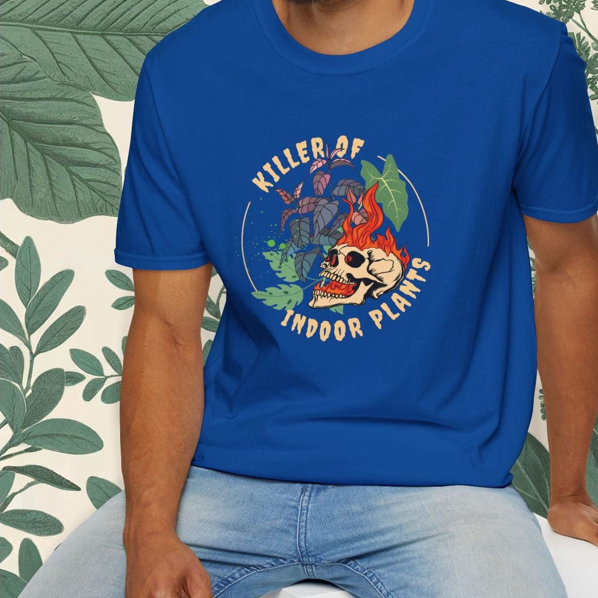 Man wearing a blue t-shirt with a graphic design sitting on a white stool.