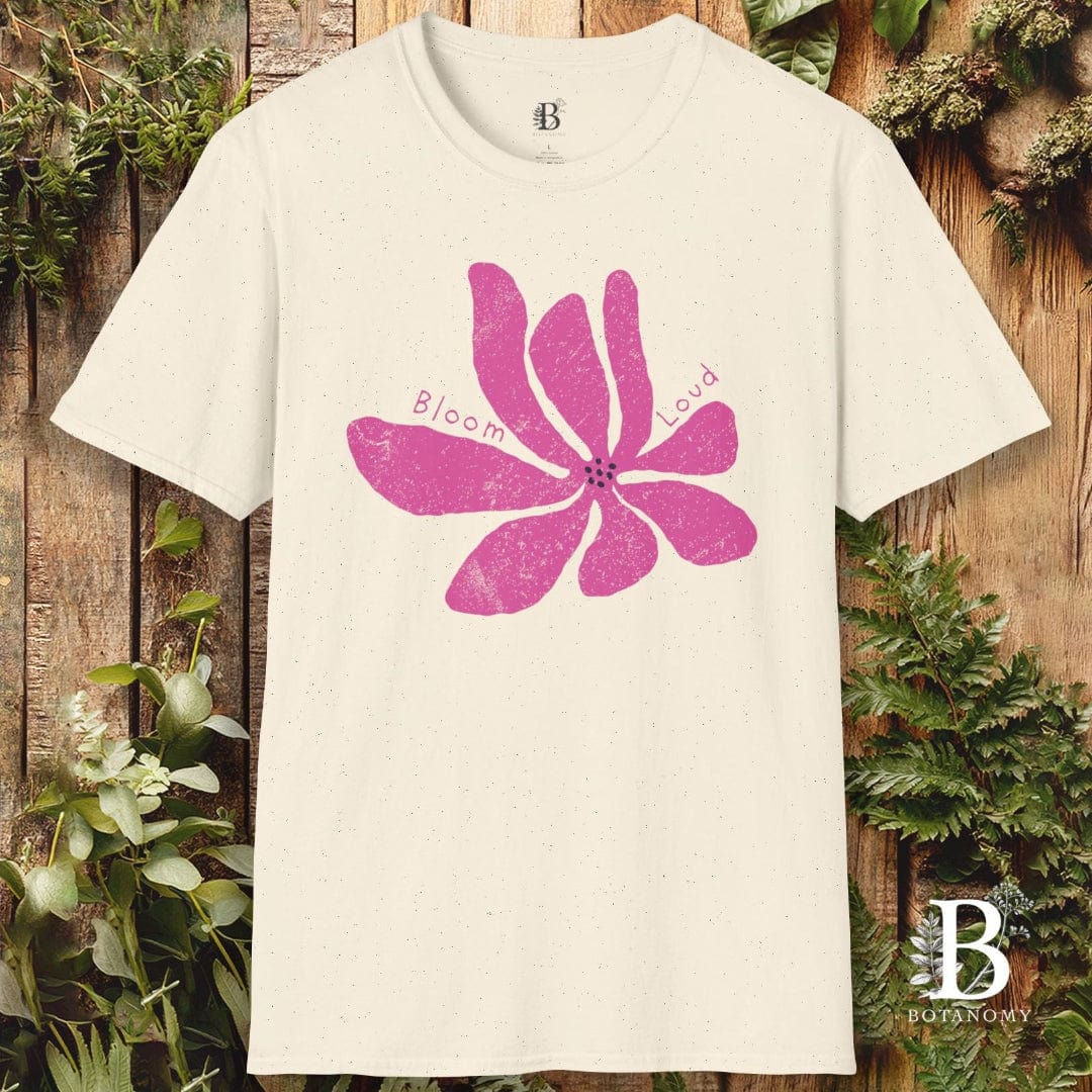 White t-shirt with pink floral design and 'Bloom' text on a wooden background