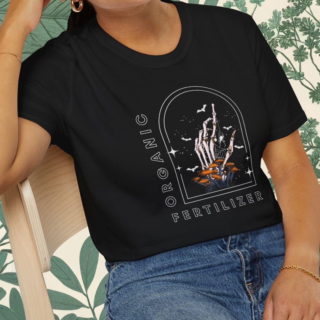 Person wearing a black t-shirt with graphic design sitting on a chair.