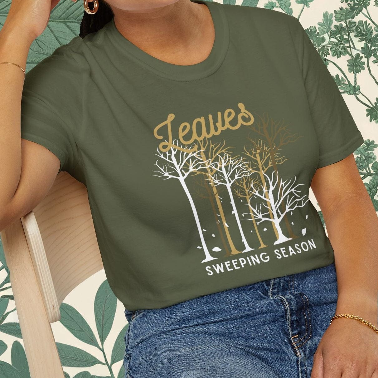 Woman wearing a green t-shirt with a leaf design and text, sitting on a chair.