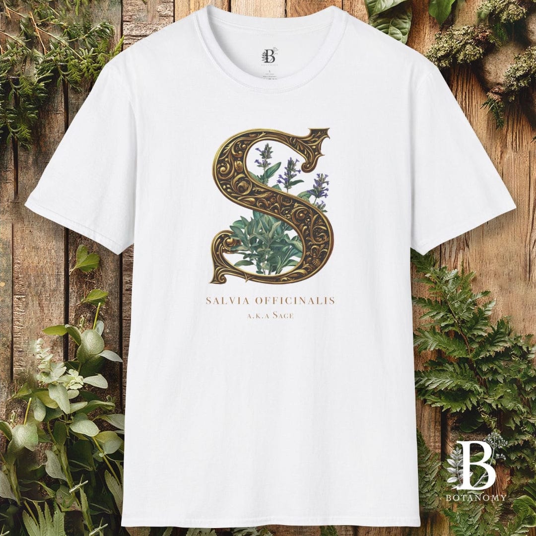 White t-shirt with decorative 'S' design and brand logo on a wooden background with plants.