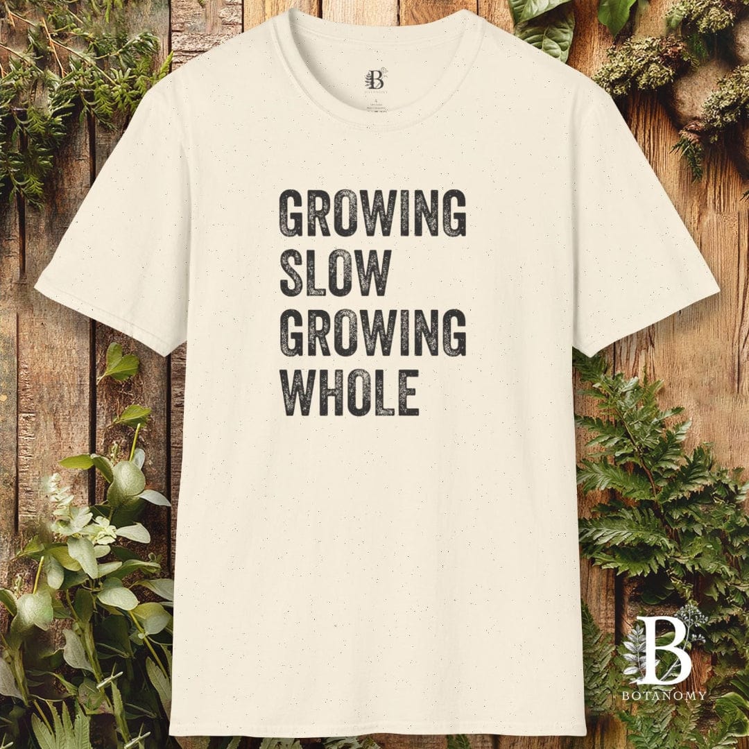 Beige t-shirt with 'Growing Slow Growing Whole' text on a wooden background with plants