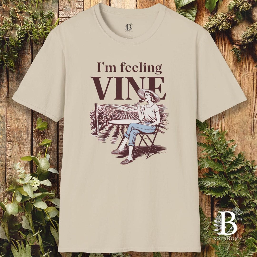 Beige t-shirt with 'I'm feeling vine' graphic design on a wooden background with plants.