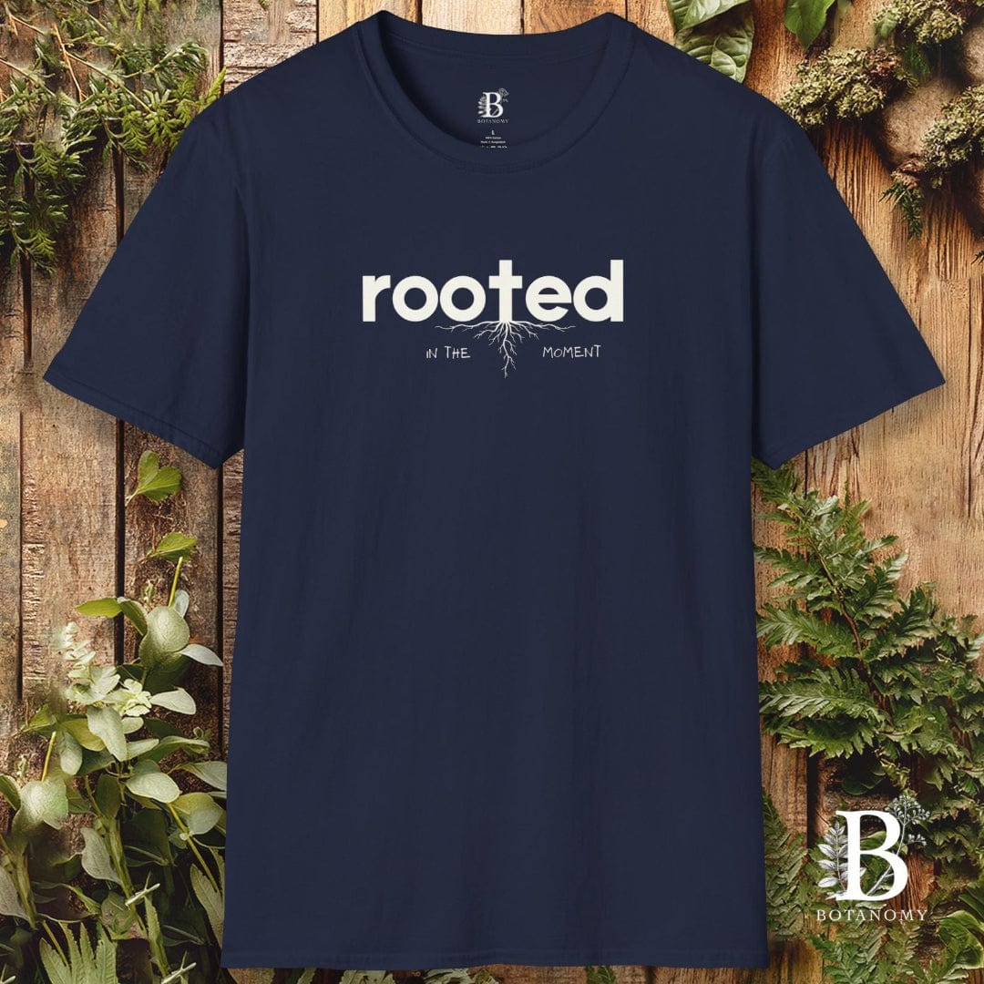 Navy blue t-shirt with 'rooted' text on a wooden background with plants