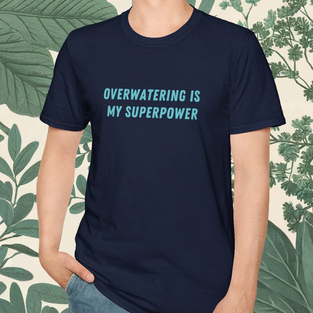 Person wearing a navy blue t-shirt with 'Overwatering is my Superpower' text, standing against a leafy background.