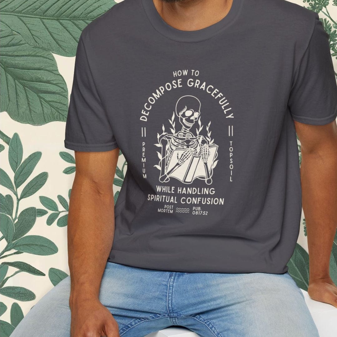 Man wearing a dark gray t-shirt with a graphic design sitting on a white stool against a light background.