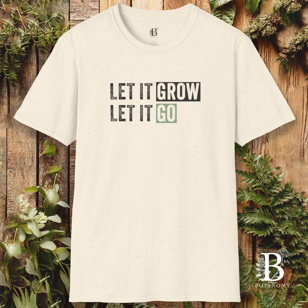 White t-shirt with 'LET IT GROW LET IT GO' text on a wooden background with plants