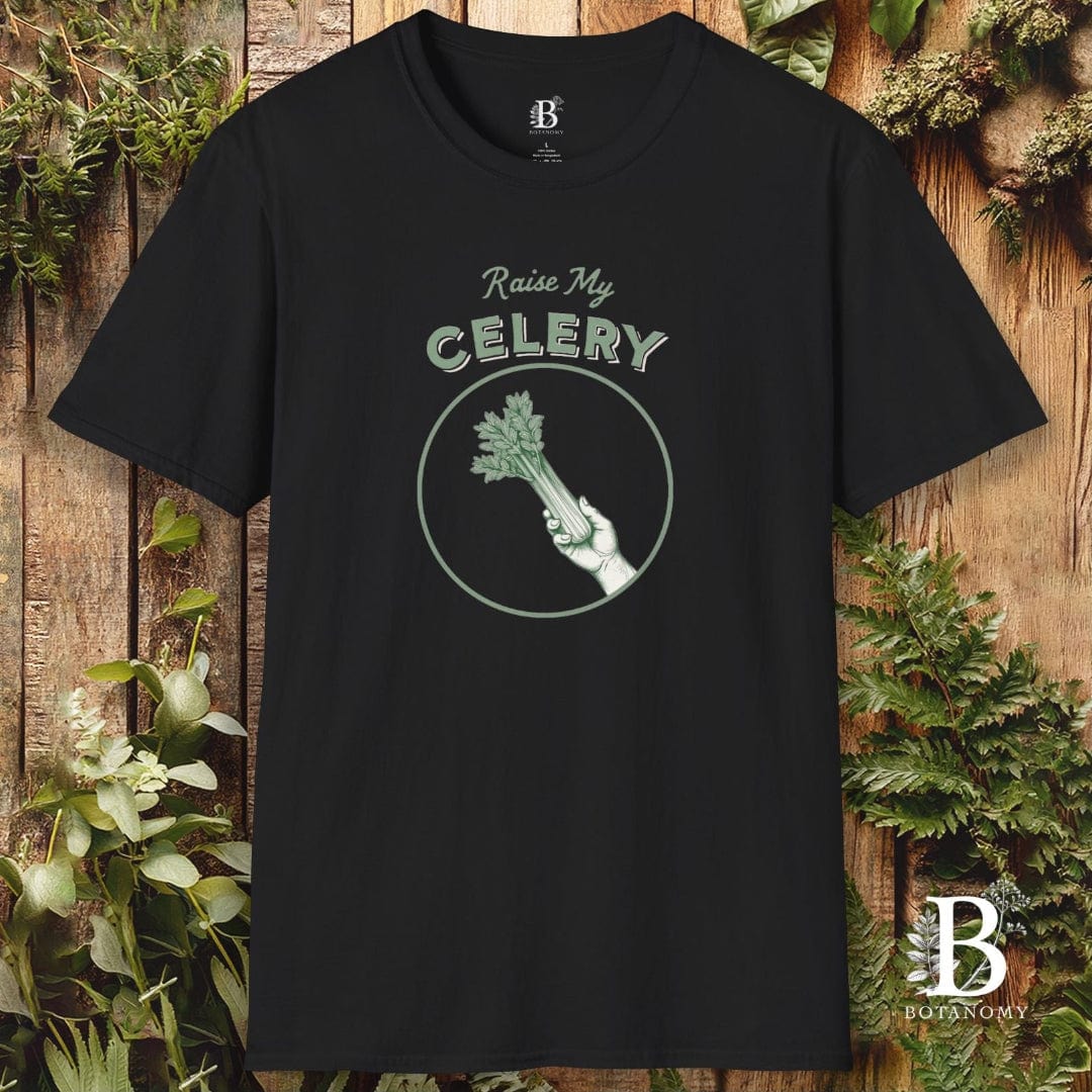 Black t-shirt with 'Raise My Celery' design on a wooden background with plants.