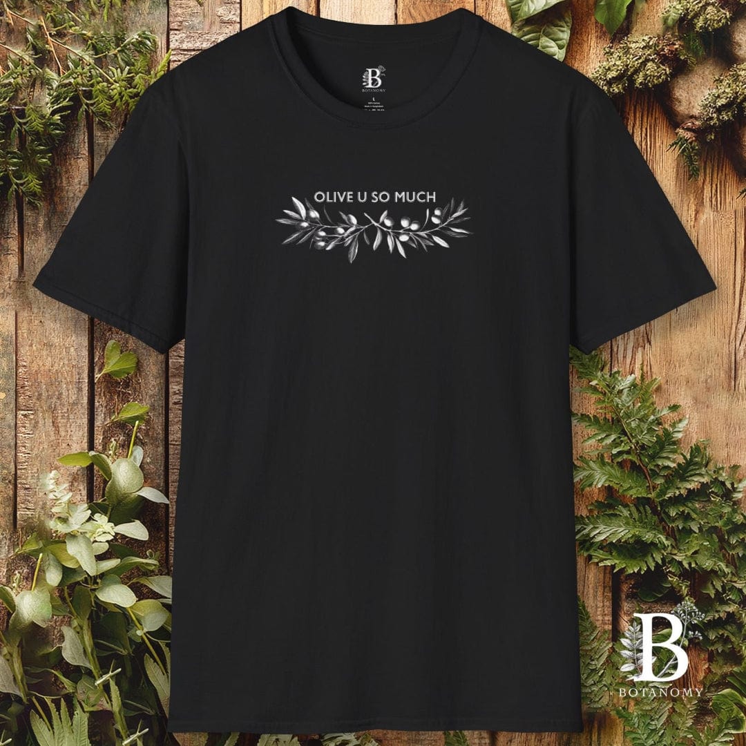 Black t-shirt with 'OLIVE U SO MUCH' text and olive branch design on a wooden background with greenery.