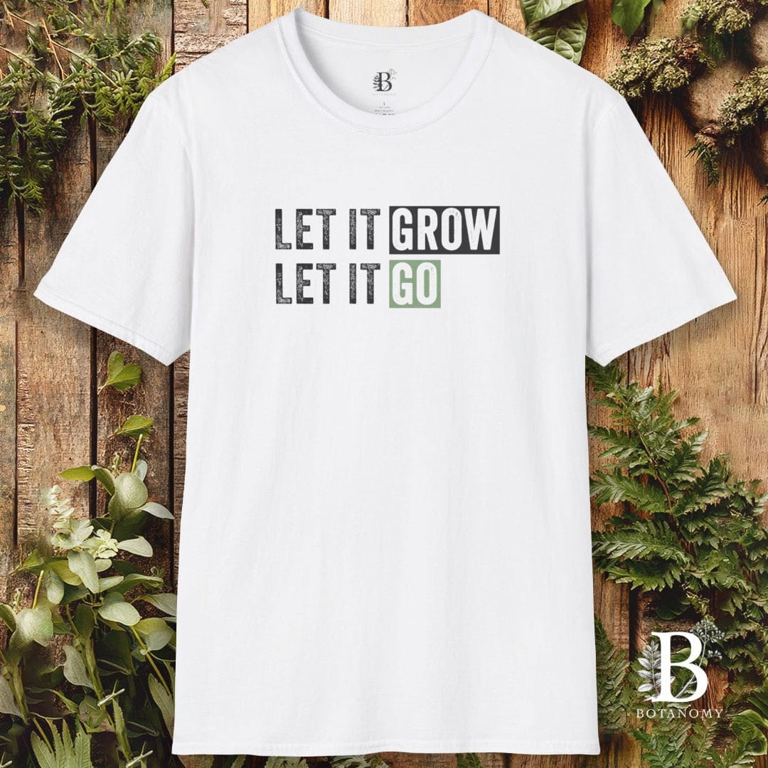 White t-shirt with 'LET IT GROW LET IT GO' text on a wooden background with plants.