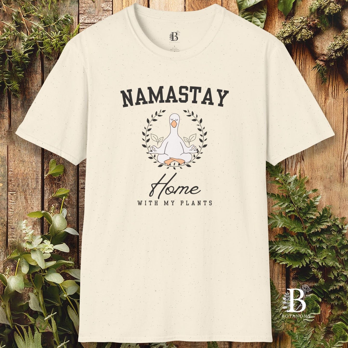 Beige t-shirt with 'Namastay Home with My Plants' design on a wooden background with plants.