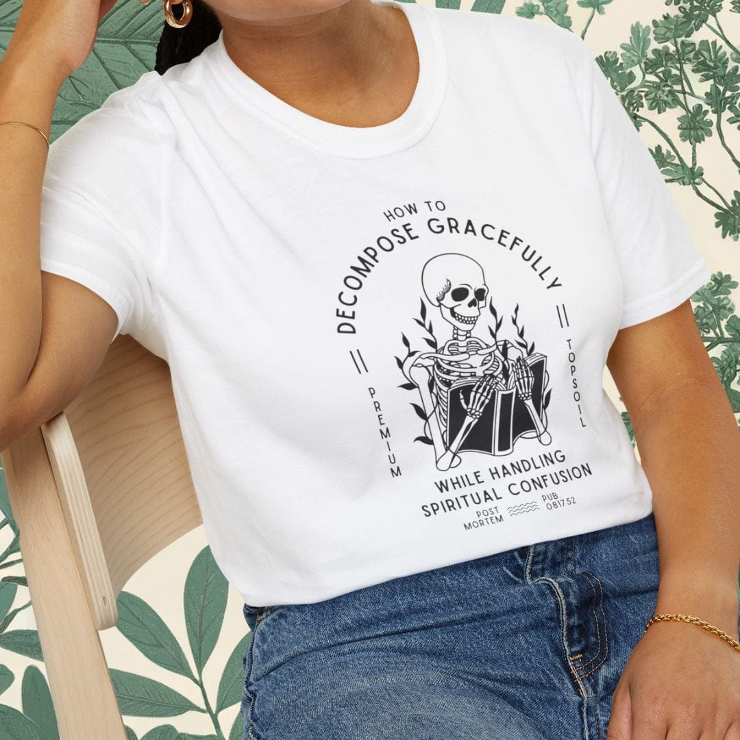 Person wearing a white t-shirt with a graphic design sitting on a chair.