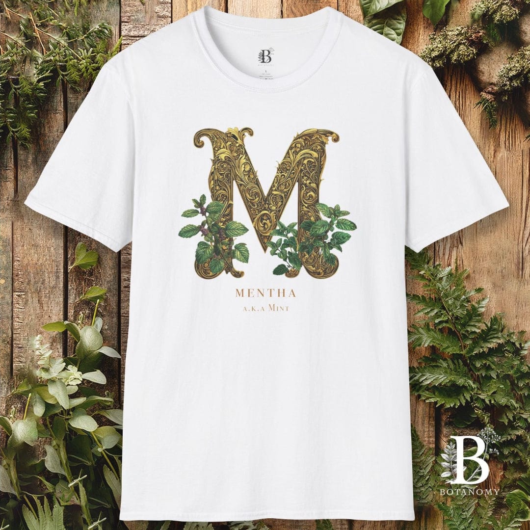 White t-shirt with decorative 'M' design and brand logo on a wooden background