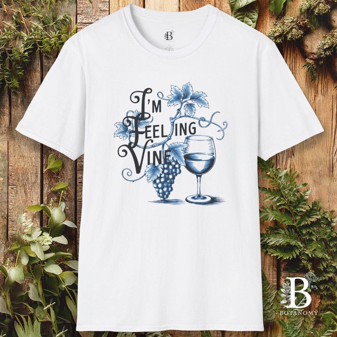 White t-shirt with 'I'm Feeling Vine' design on a wooden background with plants