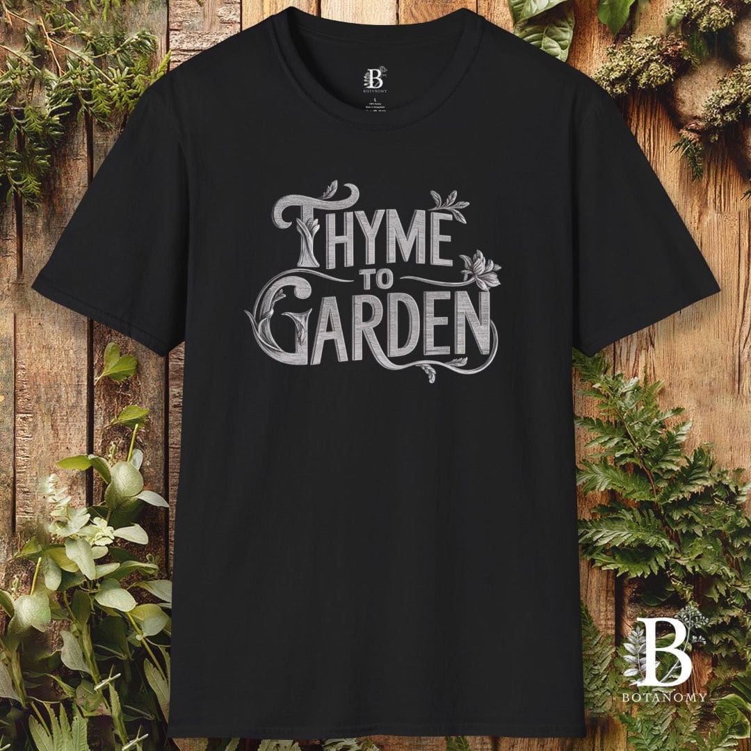 Black t-shirt with 'Thyme to Garden' text on a wooden background with plants