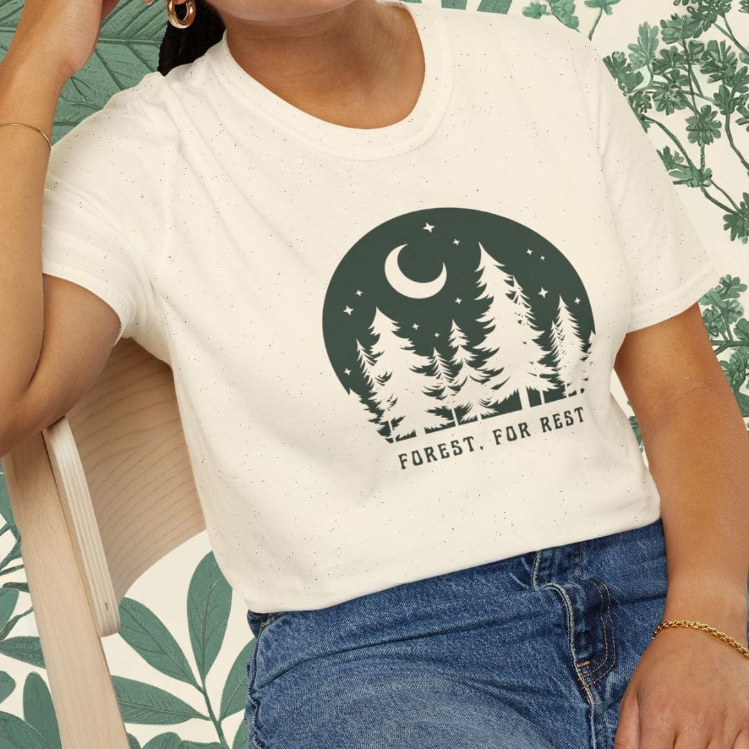 Woman wearing a white t-shirt with a nature graphic and text, sitting on a chair.