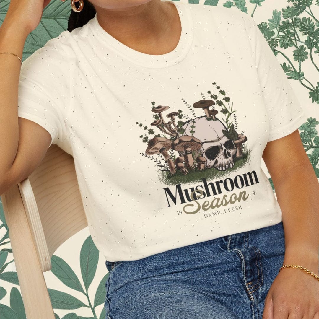 Person wearing a white t-shirt with a graphic design sitting on a chair.