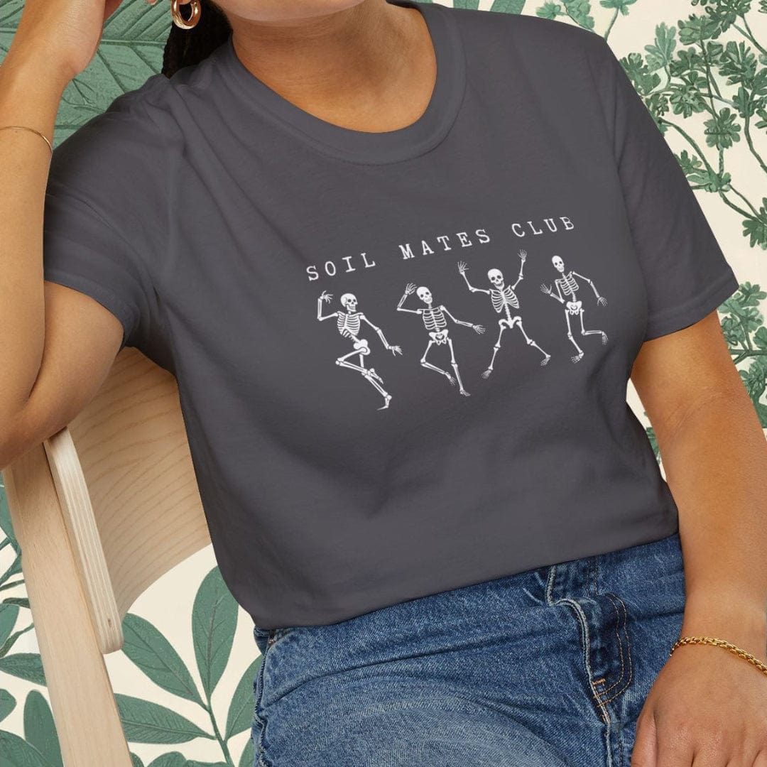 Woman wearing a dark gray t-shirt with skeleton design and text, sitting on a chair.