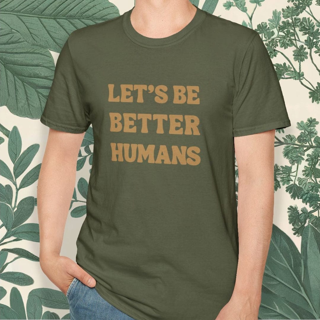 Person wearing a green t-shirt with 'LET'S BE BETTER HUMANS' text, standing against a leafy background.